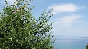 A stone-paved terrace with a stone railing overlooking a body of water. - Panorama beach (Chrani)