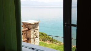 A window with a view of a calm sea and distant mountains. - Panorama beach (Chrani)