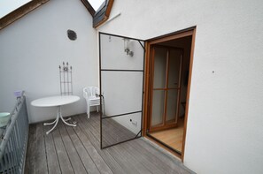 A small outdoor area with a white table and chairs, a wooden door, and a white wall with a vent. - Hofgut Metzler (Gau-Heppenheim)