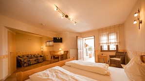 A hotel room with two beds, a sofa, a TV, and a small table. - Hofgut Metzler (Gau-Heppenheim)