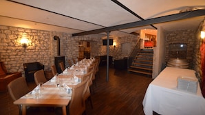 A long dining table set with white tablecloths and chairs, stone walls, and a staircase leading to an upper level. - Hofgut Metzler (Gau-Heppenheim)