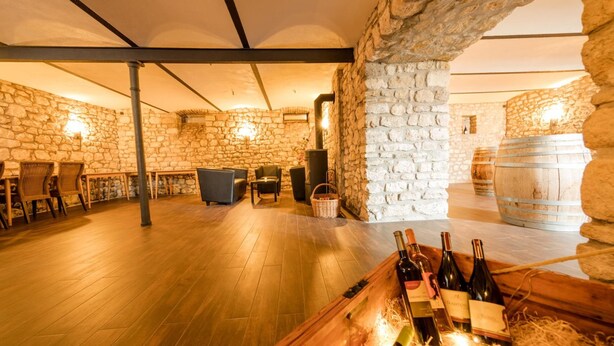 A rustic cellar with stone walls, wooden flooring, and a seating area with tables and chairs. - Hofgut Metzler (Gau-Heppenheim)