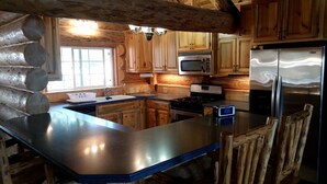 Una cucina in stile baita con mobili in legno, un frigorifero in acciaio inossidabile, un forno a microonde e un piano cottura.