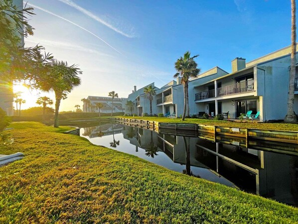 A modern hotel with a pool, reflecting the buildings and palm trees.