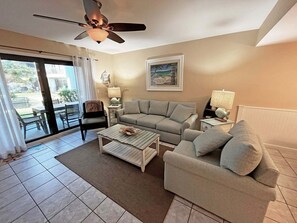 A living room with a sofa, armchairs, a coffee table, and a ceiling fan.