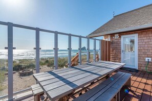 Una terraza de madera con mesas de picnic con vista a la playa.