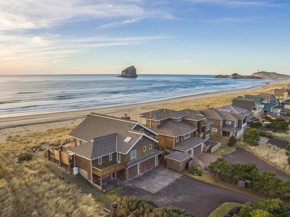 Un área residencial costera con casas, una playa y un promontorio rocoso en la distancia.