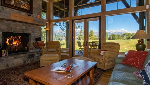 A cozy living room with a fireplace, large windows, and a view of mountains.