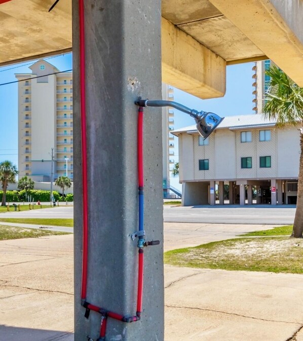 A concrete utility pole with red and blue pipes and a street lamp attached.