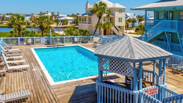 A wooden deck with a pool, lounge chairs, and a gazebo. - Farm-Chic, Updated, 2 BR Condo, Pool, Lagoon Access, Walk To Beach! Cove 208A (Gulf Shores)