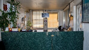 Zona de recepción con mostrador de mármol verde, cámara de seguridad y monitor de computadora mostrando imágenes de videovigilancia.