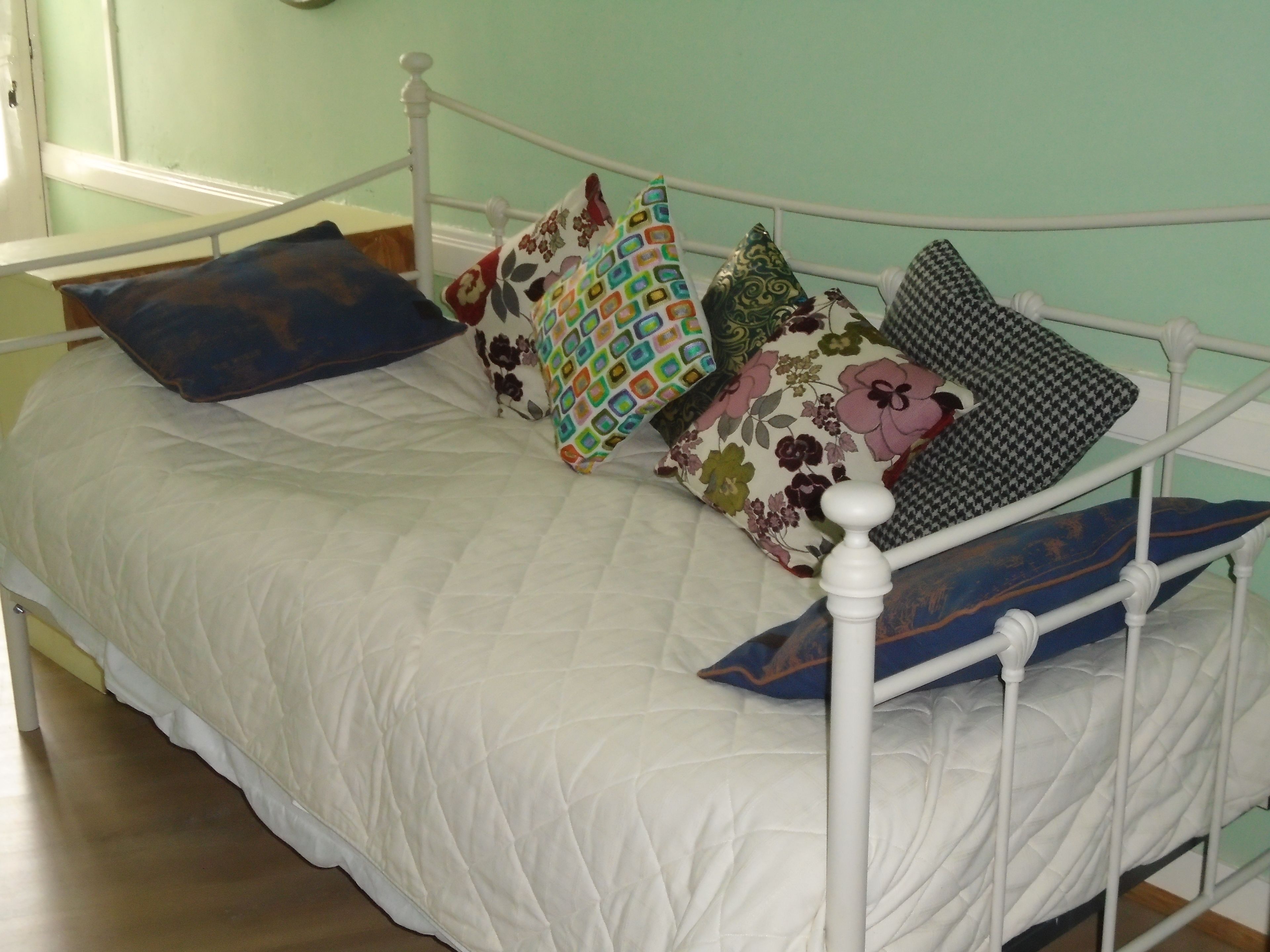 Un lit avec une couette blanche et plusieurs coussins de couleurs vives.