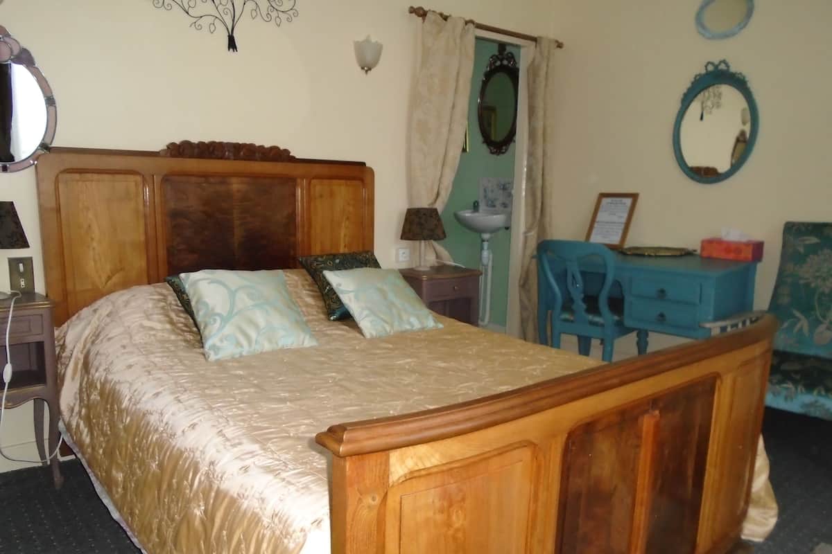 Ein Schlafzimmer mit einem Holzbett, einem Nachttisch, einem Schreibtisch, einem Stuhl und einem Spiegel.