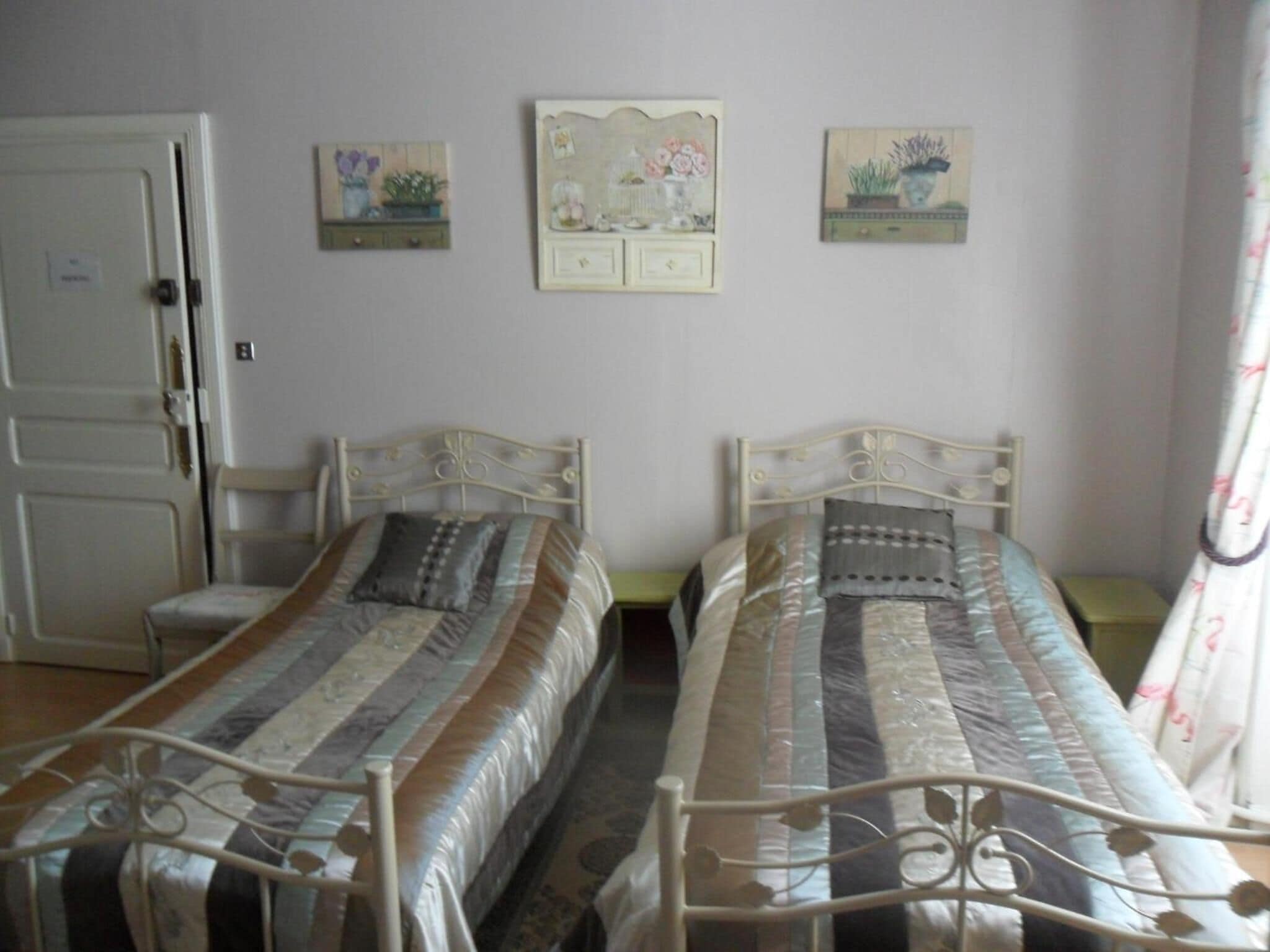 A room with two metal beds, a white door, and two wall-mounted cabinets with floral decorations.