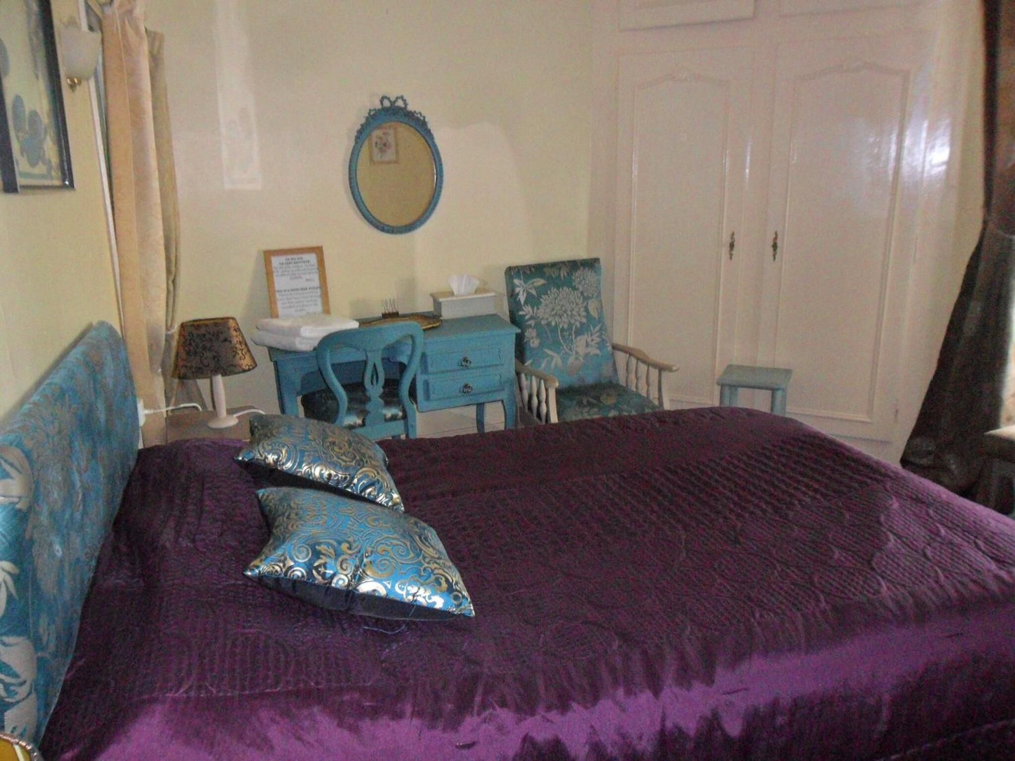 A bedroom with a large bed, a dresser, a chair, and a desk.