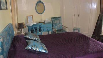 A bedroom with a large bed, a dresser, a chair, and a desk.