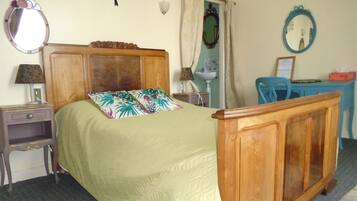 A bedroom with a wooden bed, a nightstand, a desk, a chair, and a mirror.