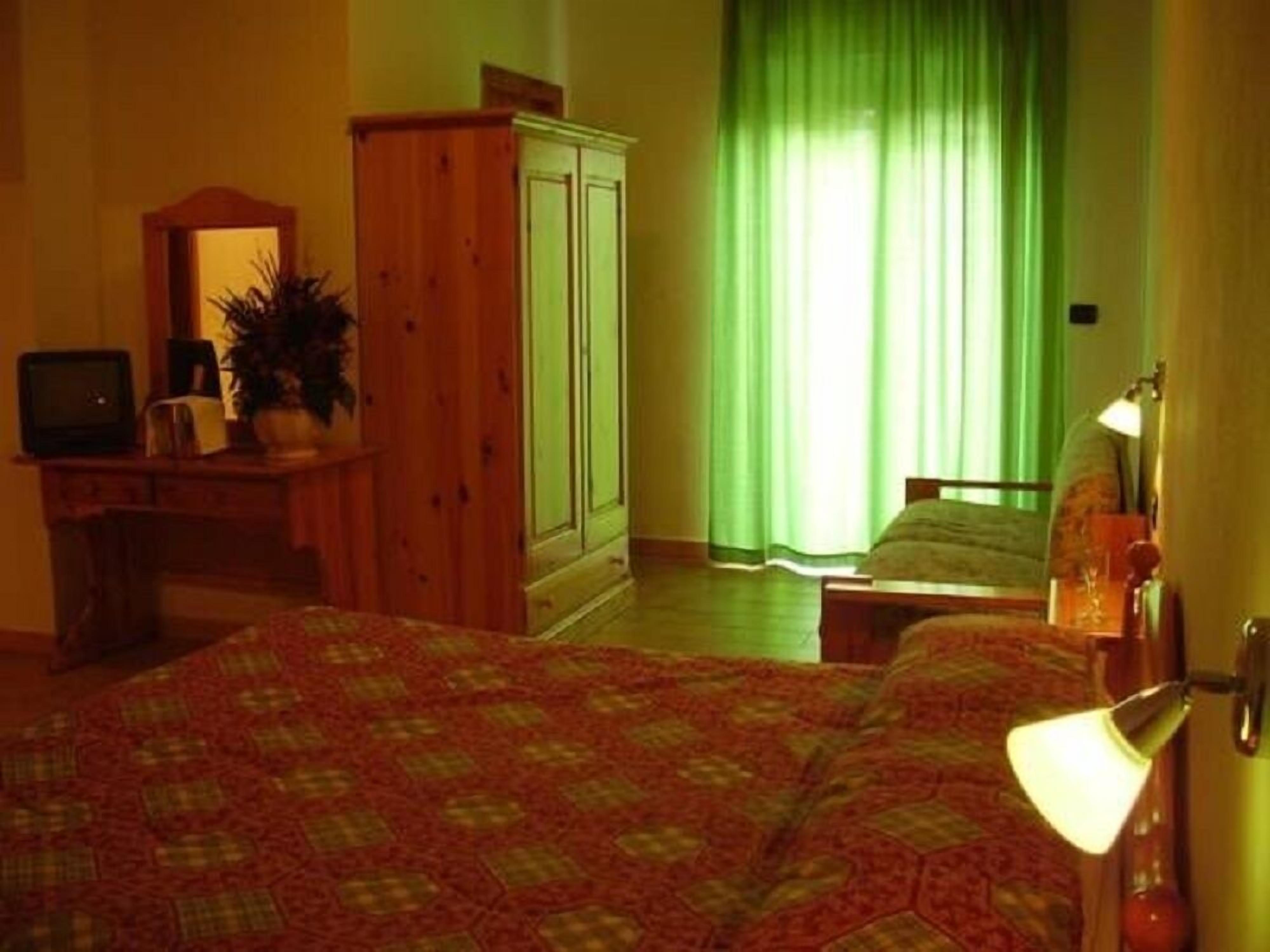 Ein Zimmer mit Bett, Schreibtisch, Kleiderschrank und Fernseher.