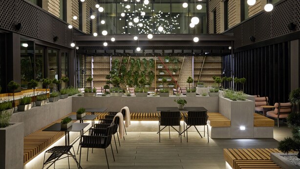 An indoor courtyard with seating areas, potted plants, and hanging lights.