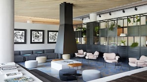 A modern lobby with a checkered floor, grey sofas, a central coffee table, and a large pillar.