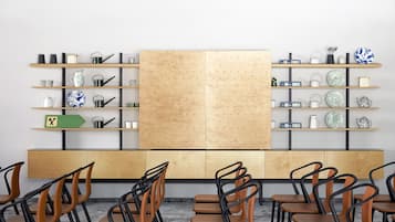 A modern room with wooden furniture, shelves with decorative items, and a large pegboard wall.