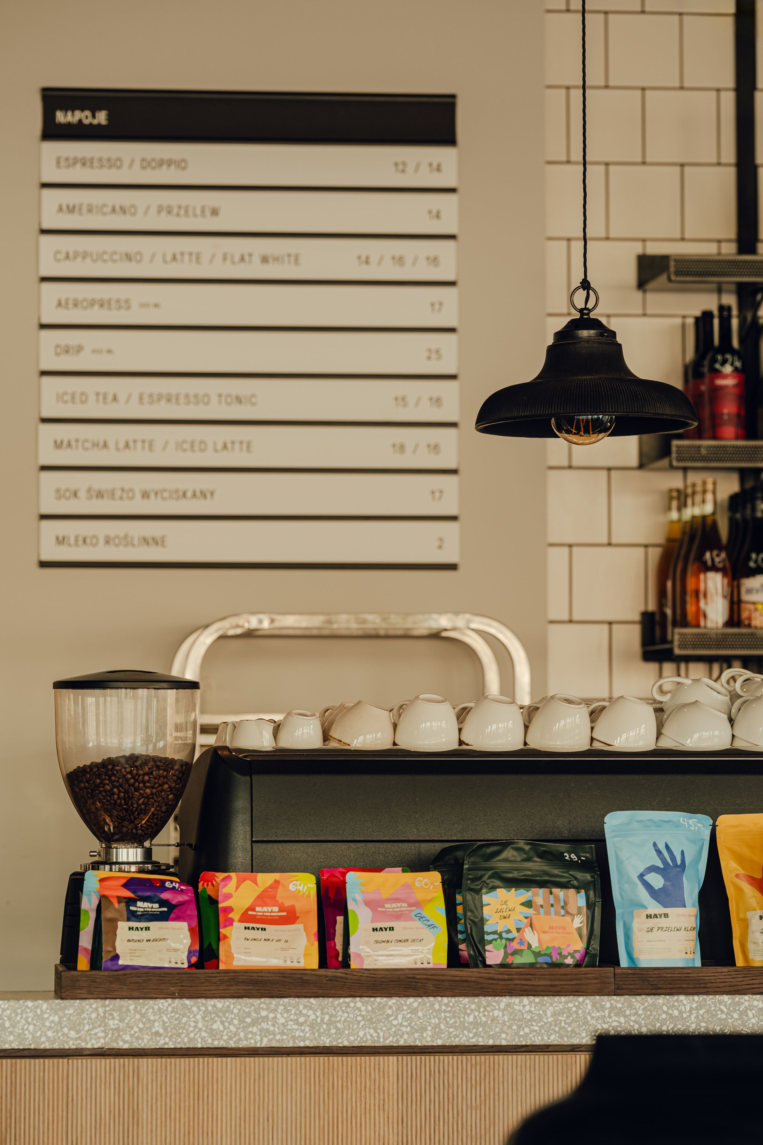 Mostrador de cafetería con un menú que enumera diversas opciones de café y un molinillo.