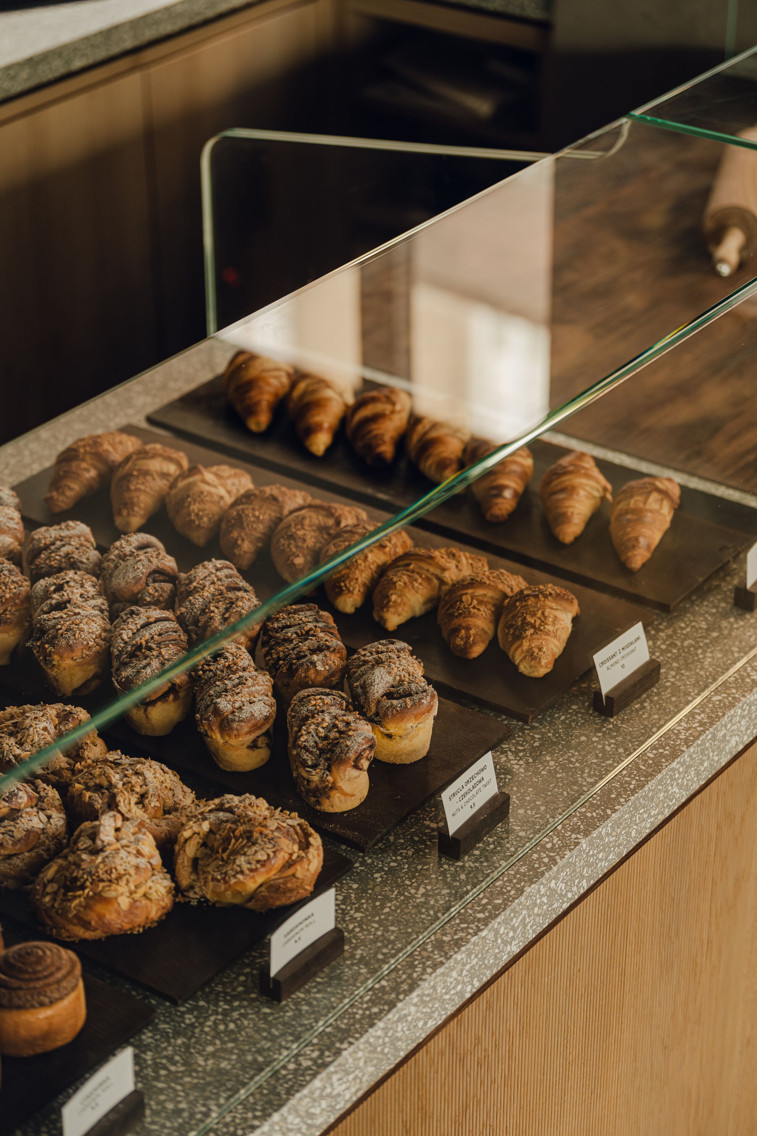Une vitrine de boulangerie où sont exposés divers produits de pâtisserie, notamment des croissants et des pains aux cannelle.