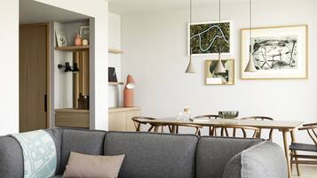 A modern living room with a grey sofa, wooden dining table, and pendant lighting.