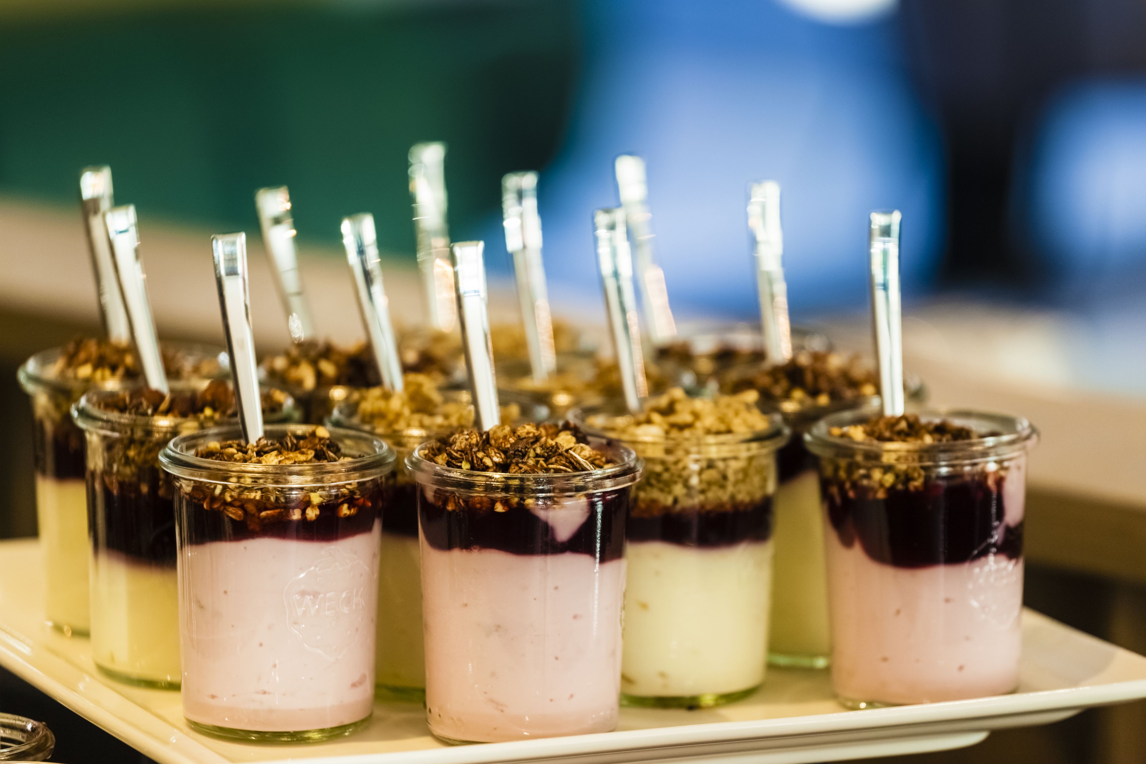 En bakke med lagdelte dessertglas, pyntet med granola og sugerør.