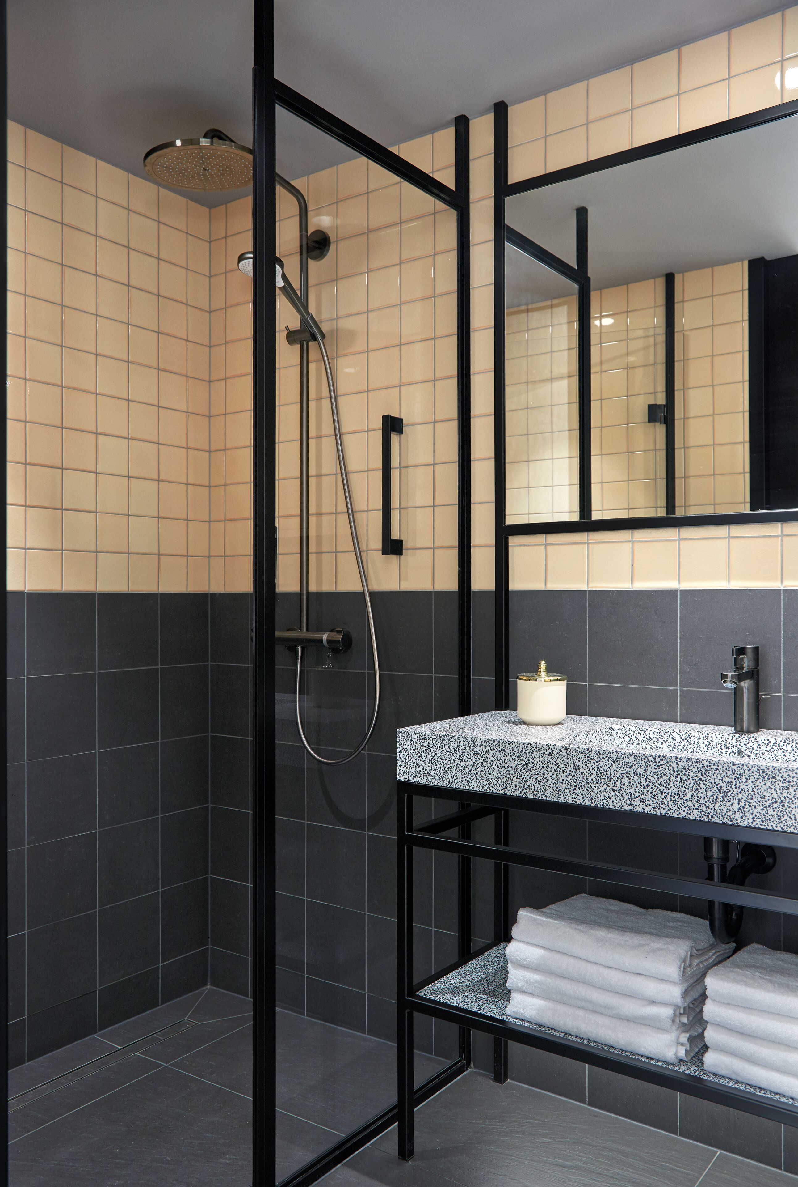 Un baño moderno con ducha, un lavabo con espejo y un estante con toallas.