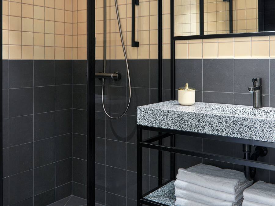 Un baño moderno con ducha, un lavabo con espejo y un estante con toallas.