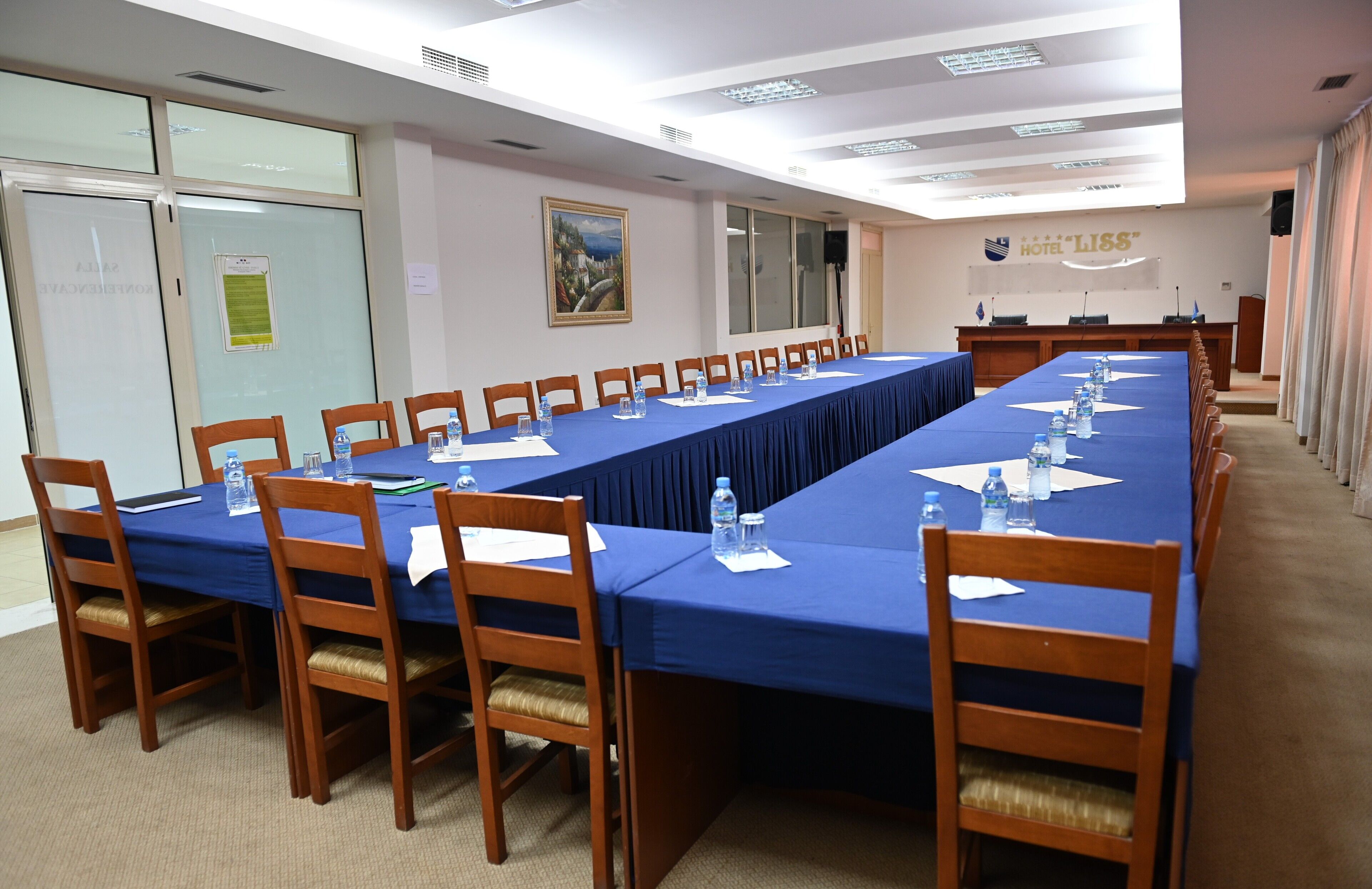 A conference room with a long table, chairs, water bottles, and documents.