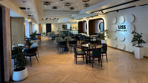 A modern bar and coffee lounge with wooden flooring, multiple seating areas, and a bar counter. - Hotel Liss (Lezhe)