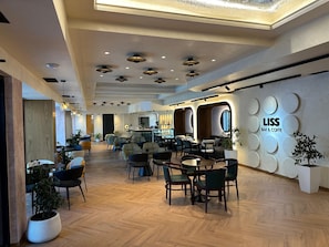 A modern bar and coffee lounge with wooden flooring, multiple seating areas, and a bar counter. - Hotel Liss (Lezhe)