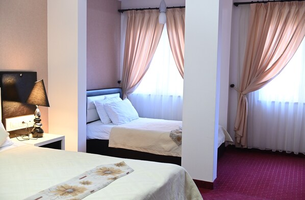 A hotel room with a bed, a nightstand with a lamp, and a window with curtains.