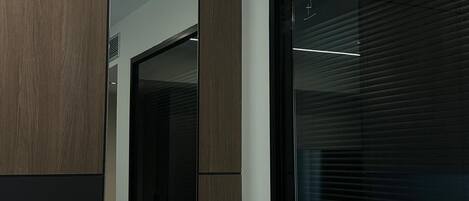 Una habitación de hotel moderna con un amplio ventanal corredera, un sofá gris y un panel de pared de madera.
