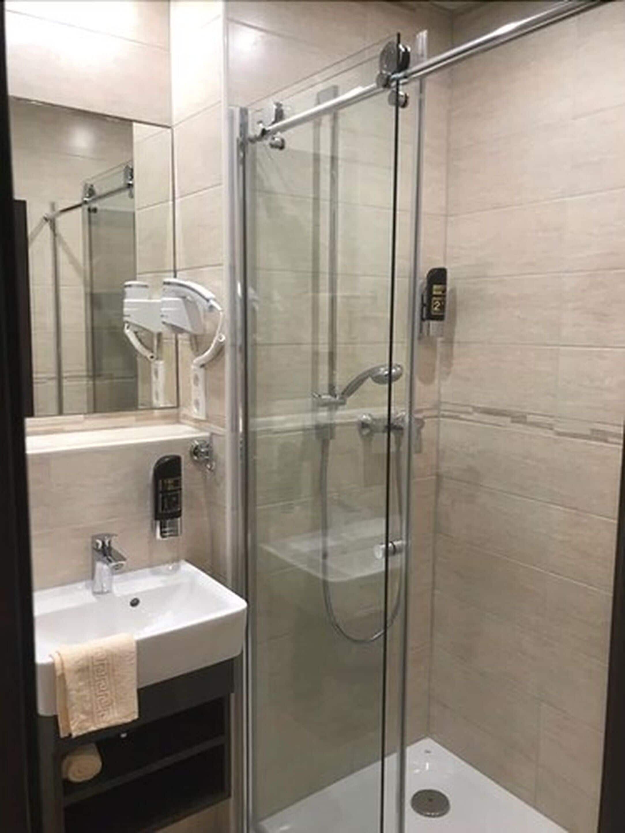 A modern bathroom with a glass-enclosed shower, a white sink, and a towel hanging on the wall.