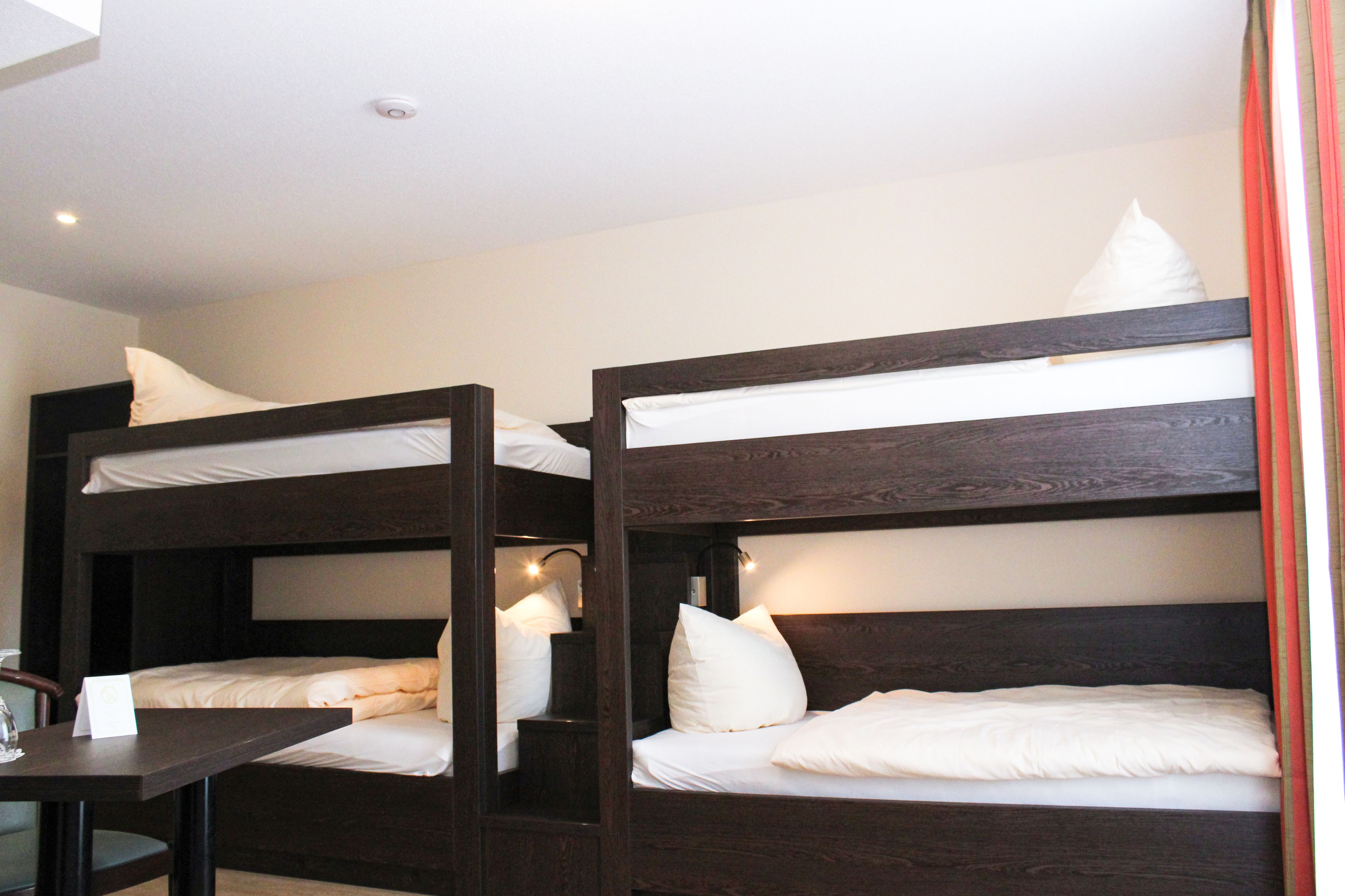 A bunk bed room with a table and a lamp.