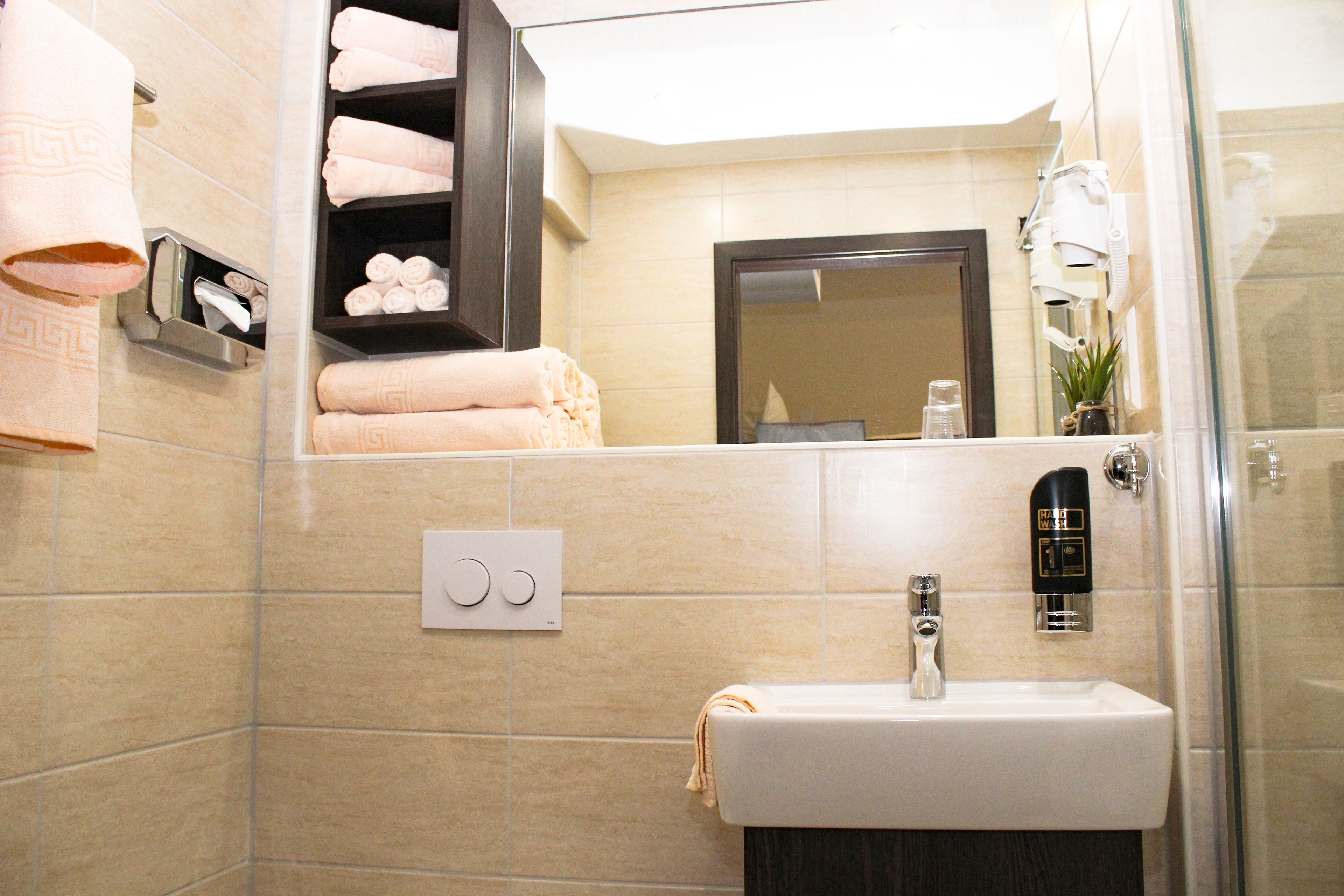 Un baño con lavamanos, toallero y espejo.