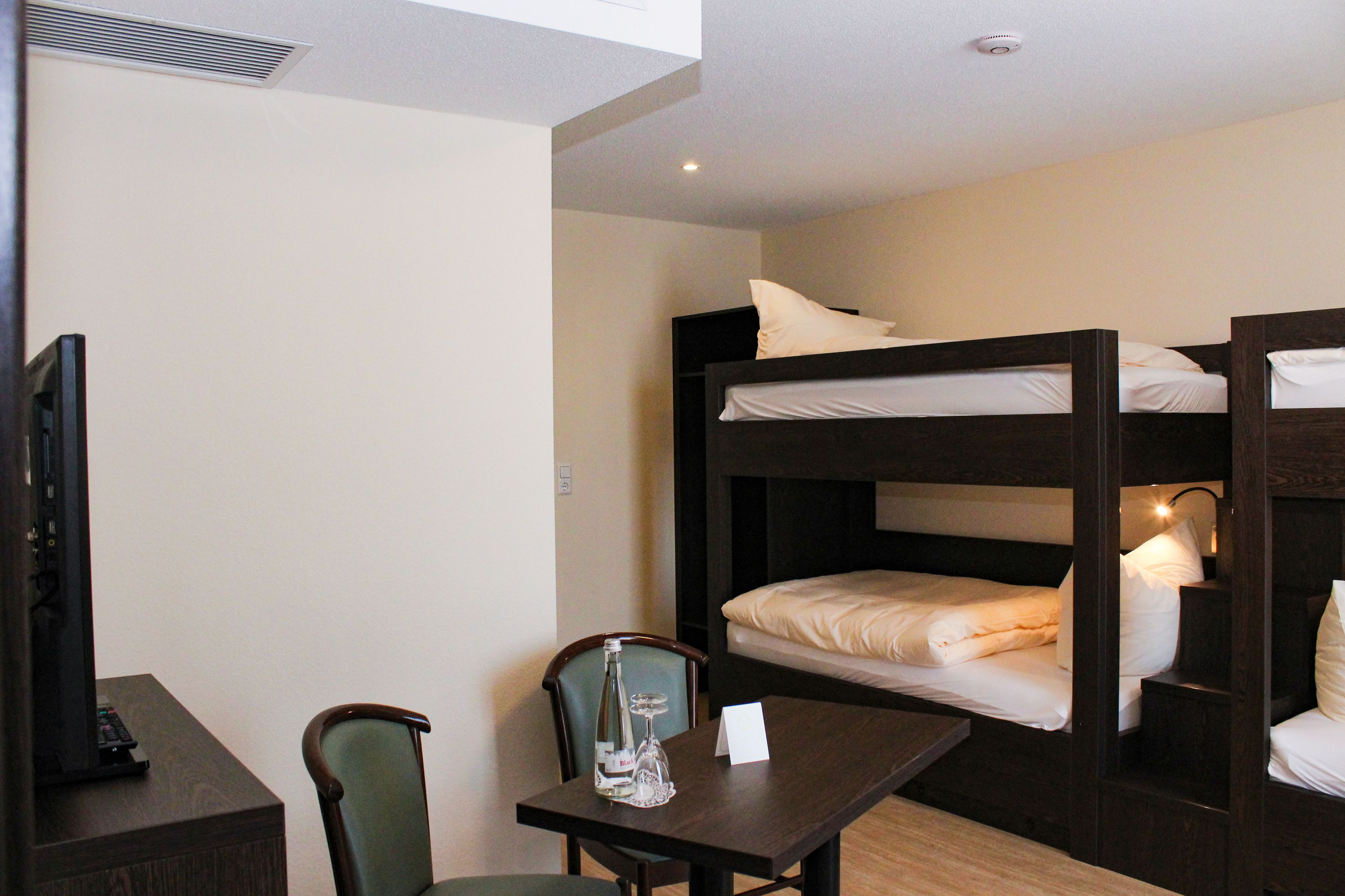 A bunk bed room with a desk, chair, and a television.