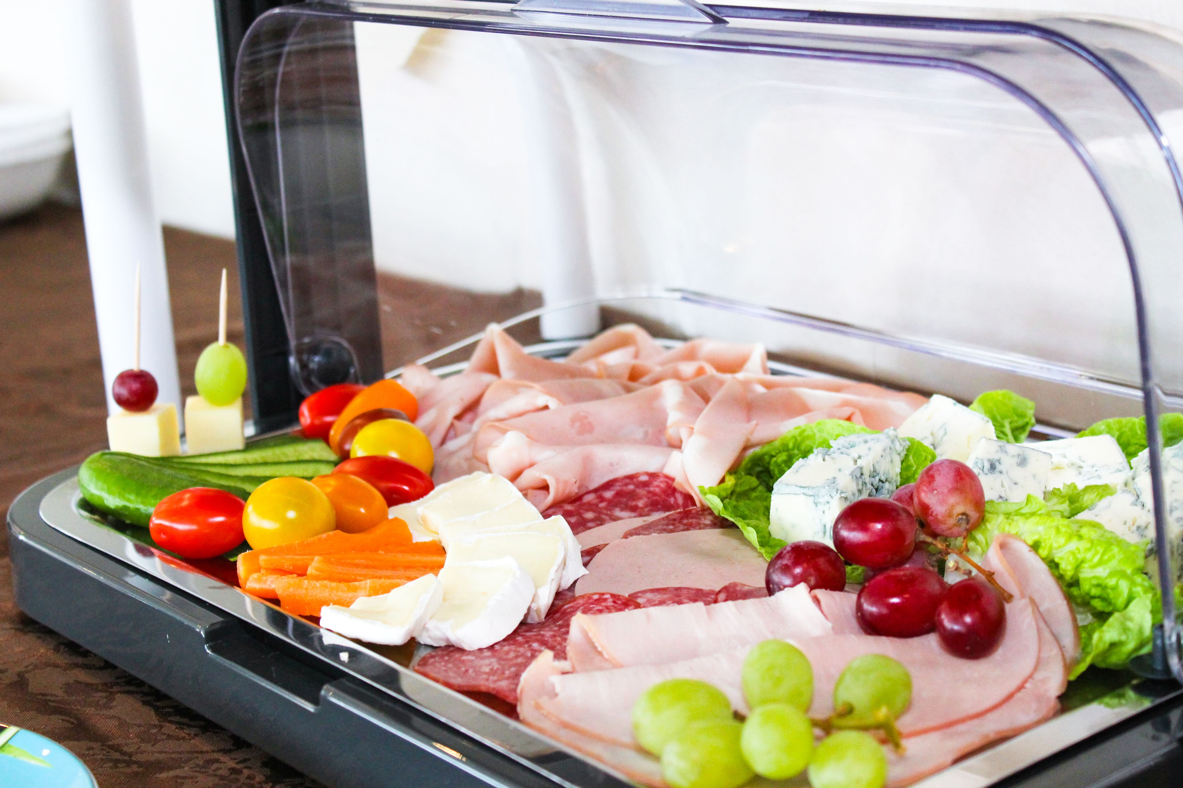 A tray of assorted deli items including meats, cheeses, and vegetables.