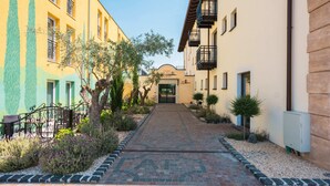 A courtyard with a paved walkway, surrounded by buildings with balconies and a restaurant entrance. - Hotel La Toscana Nähe Europapark  mit Ticket Garantie (Ringsheim)