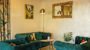 A room with a green sofa set, a floor lamp, a mirror, and a painting on the wall. - Hotel La Toscana Nähe Europapark  mit Ticket Garantie (Ringsheim)