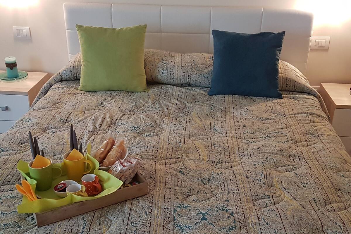Un lit bien fait, avec une couvre-lit à motifs, deux oreillers et un plateau contenant des collations et des boissons.