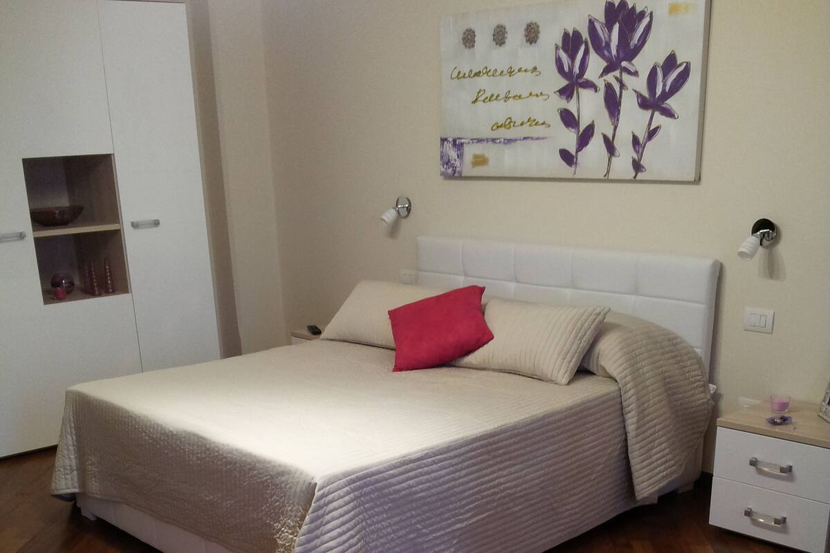 Une chambre à coucher comprenant un lit, une table de chevet, une armoire et une œuvre d’art accrochée au mur.