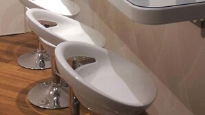 A modern kitchen with a long counter, white bar stools, and a variety of kitchenware and appliances. - B&B Residenza Piazza Moro (Bari)