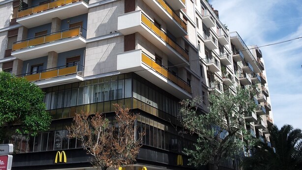 A multi-story building with balconies, a McDonald's restaurant, and parked cars. - B&B Residenza Piazza Moro (Bari)