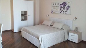 A bedroom with a bed, bedside tables, a wardrobe, and a wall-mounted artwork. - B&B Residenza Piazza Moro (Bari)
