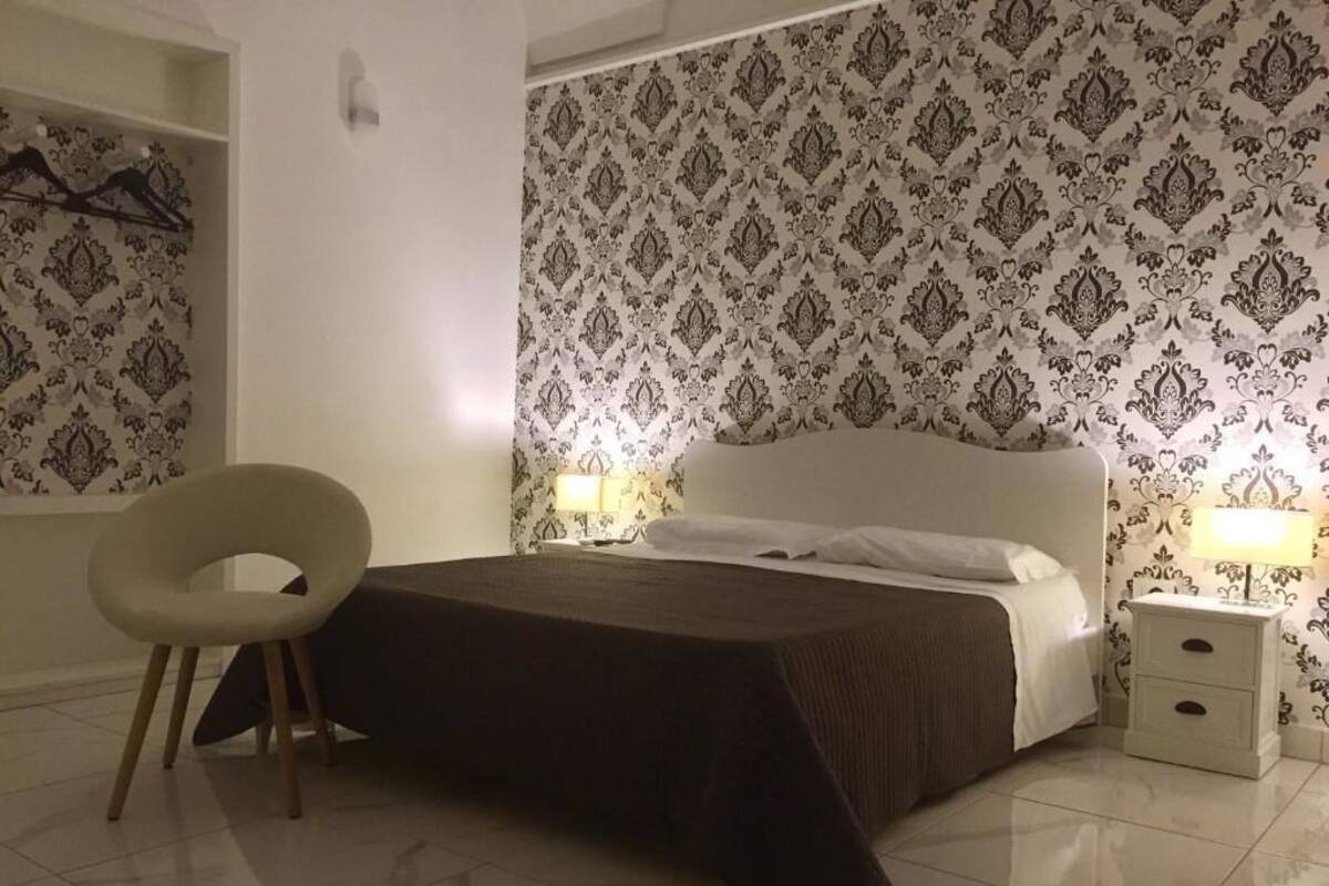 Ein Schlafzimmer mit einem Bett, Nachttischlampen, einem Sessel und einem Nachttisch.
