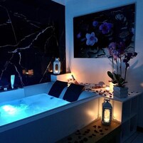 Un baño moderno con una bañera grande, una pared de mármol y una pintura de flores.
